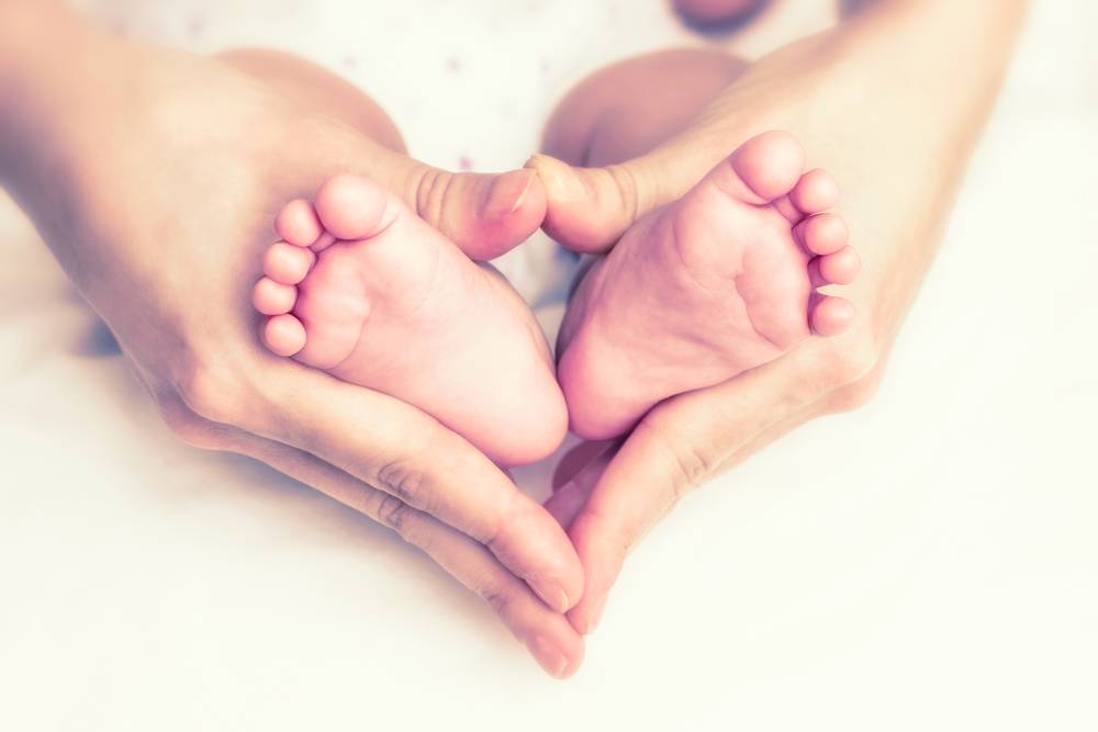 someone holding a baby's feet to form the shape of love