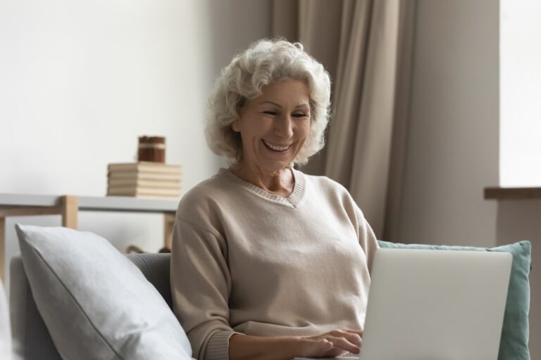 Happy senior lady making video call on laptop from home