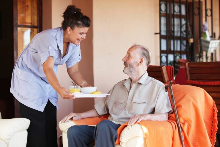 Woman serving soup and fruits to a middle-aged man.