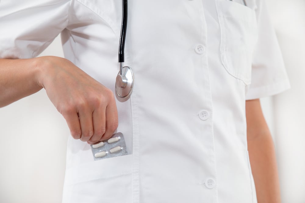 A doctor putting medication in his pocket