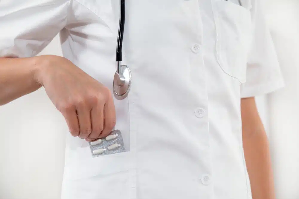 A doctor putting medication in his pocket