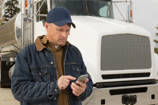 Truck driver texting next to truck