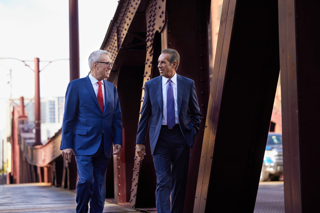 Steven Levin and John Perconti walking and talking on bridge in downtown Chicago