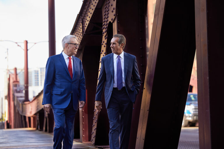 Personal injury attorneys Steven Levin and John Perconti walking and talking on bridge in downtown Chicago
