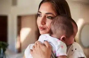 Hispanic woman in D.C. holding her baby, looking outside