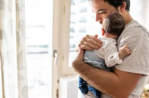 Maryland father standing holding his newborn who has birth injuries 