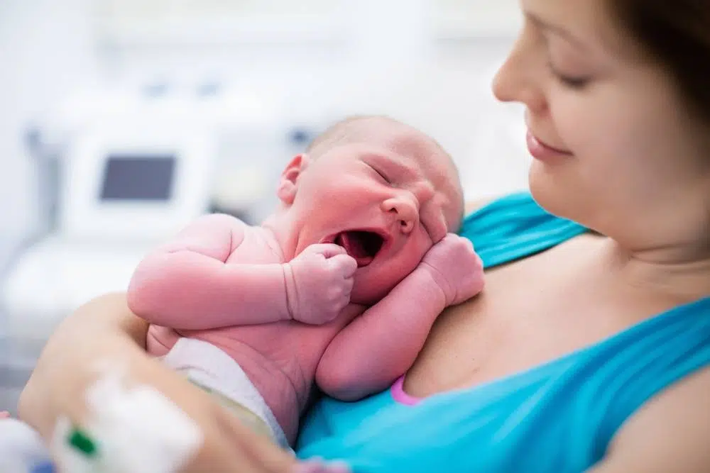 Image of baby crying while laying on his mom's chest