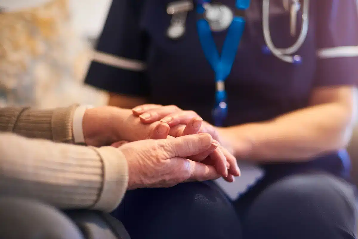 Nurse holding an elderly patient's hand