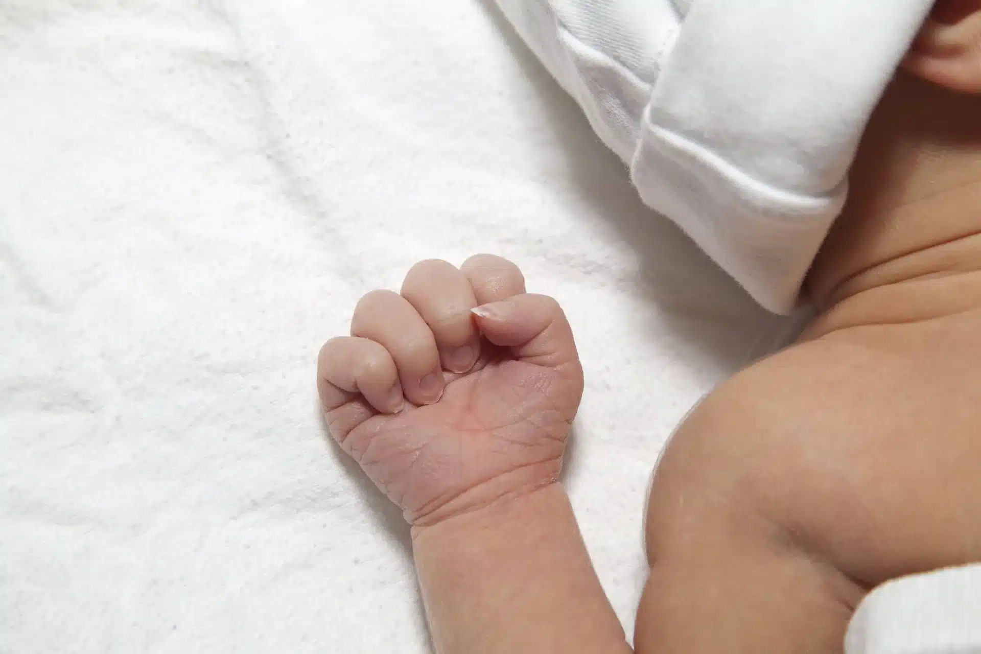 A new born baby with one hand tight-fisted