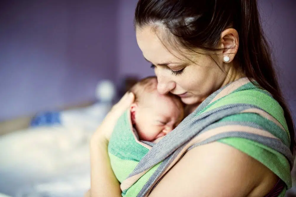 A nursing mother holding a new born baby tight to her chest