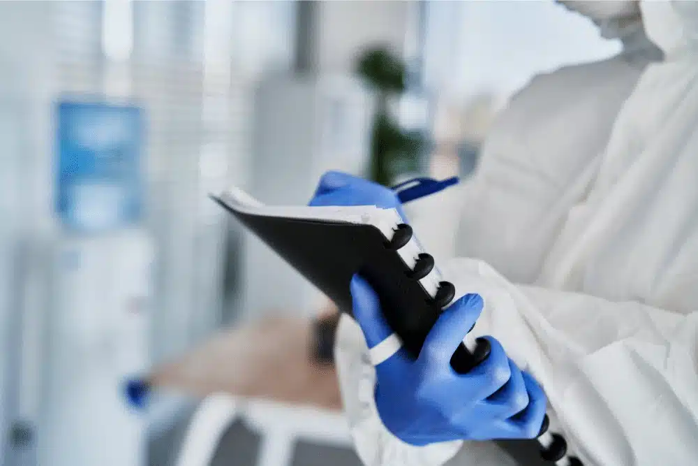 Medical professional in blue gloves writing on a hospital file
