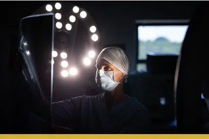Doctor or nurse reviewing an x-ray in a dark room, there are lights behind her