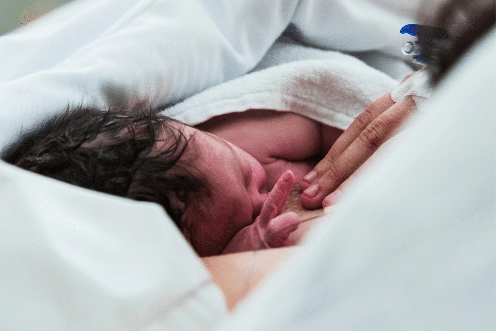 newborn baby wrapped in a blanket, laying on mom's chest