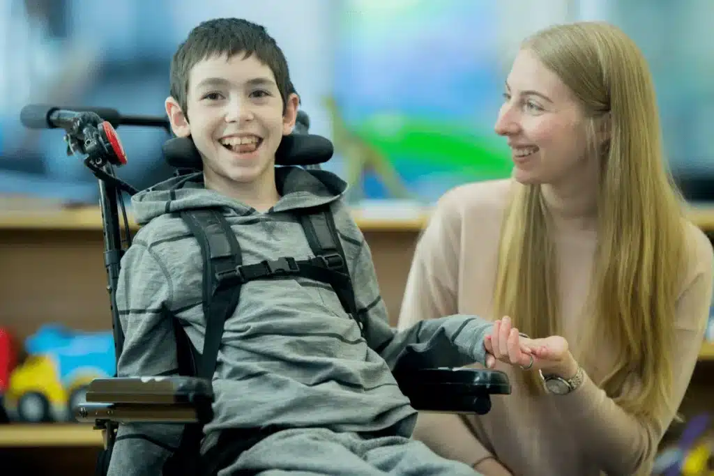 Image of a smiling child on a wheelchair with his mom