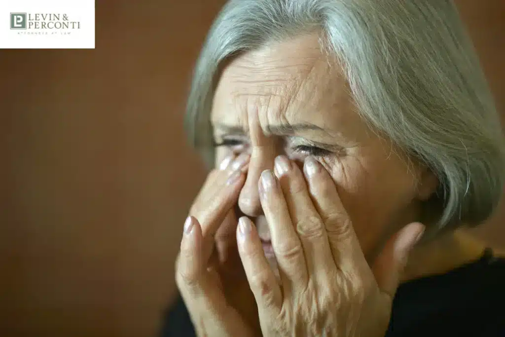 Elderly woman covering her face and appearing distressed