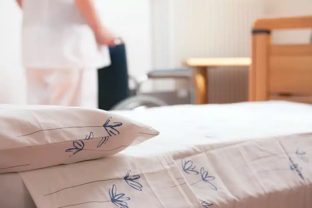 Neatly made hotel or hospital bed with white linens and decorative pillows