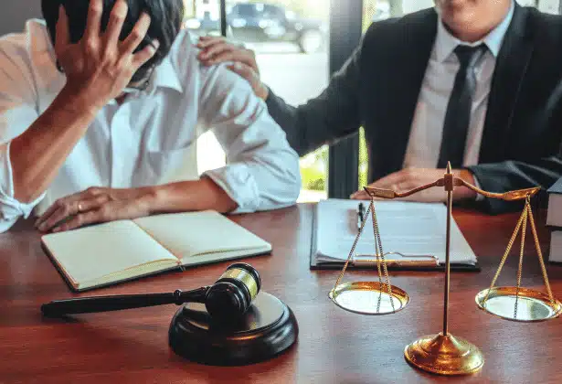 Emotional legal consultation with distressed clients and attorney discussing case with gavel and scales on conference table