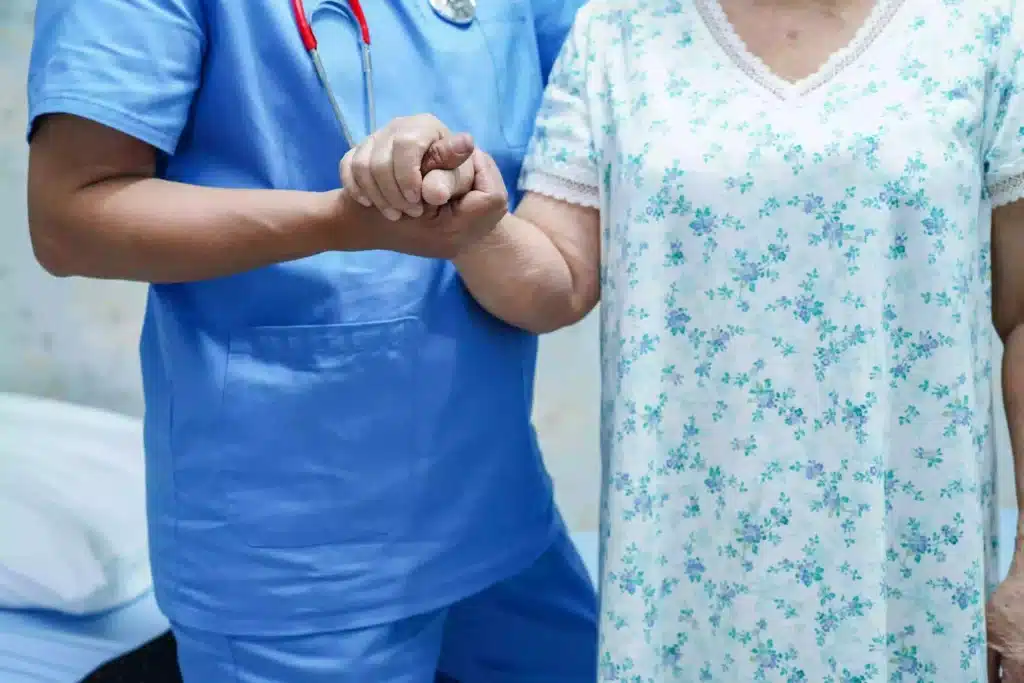 nursing home staff holding an elderly woman's hand