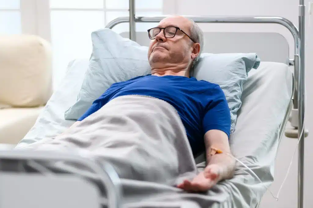 Elderly male patient with IV line resting in hospital bed