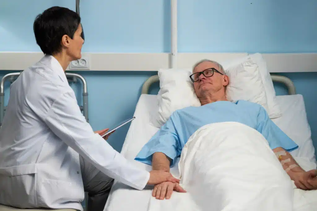 Doctor consulting with elderly male patient in hospital bed