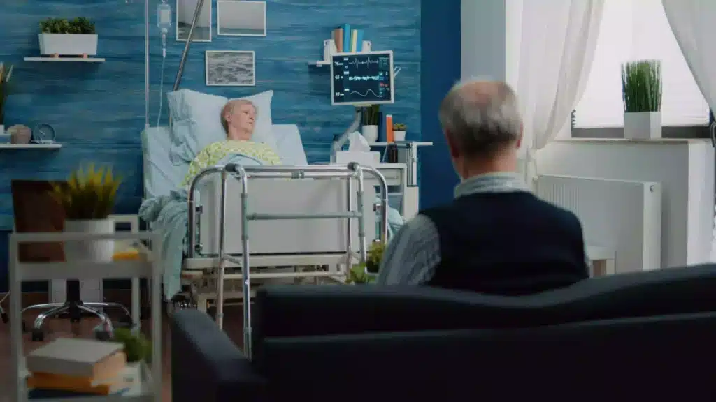 Elderly patient resting in a hospital bed with a monitor beside her