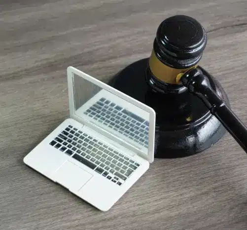 Miniature laptop computer next to wooden gavel on desk