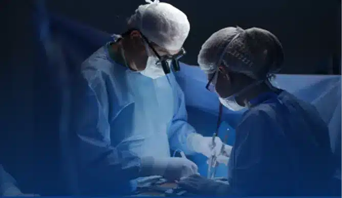 Surgeon in blue scrubs performing surgery in an operating room