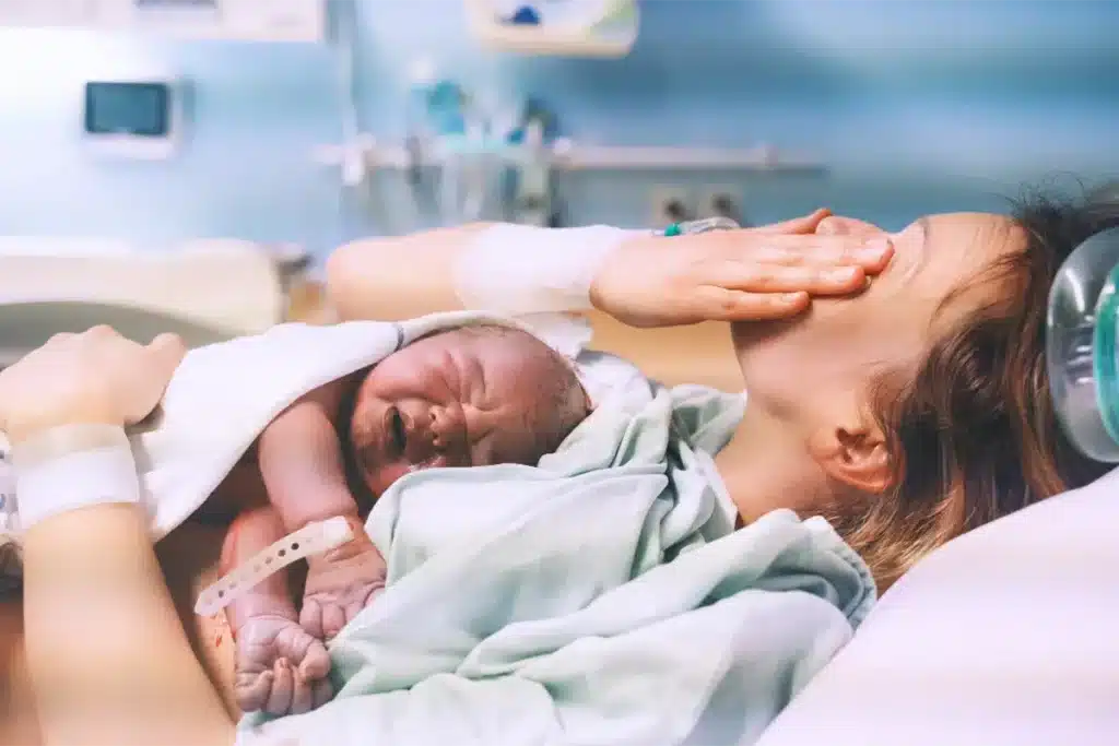 Mother holding newborn baby immediately after delivery in hospital