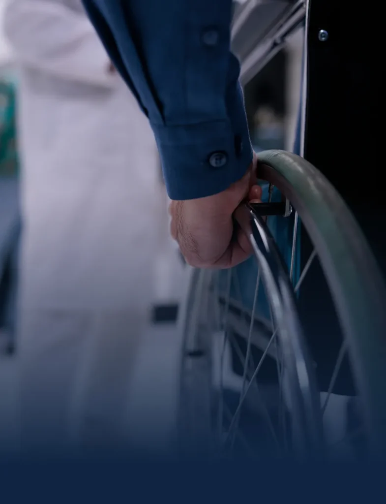 Man's hand on a wheelchair wheel pushing himself forward.