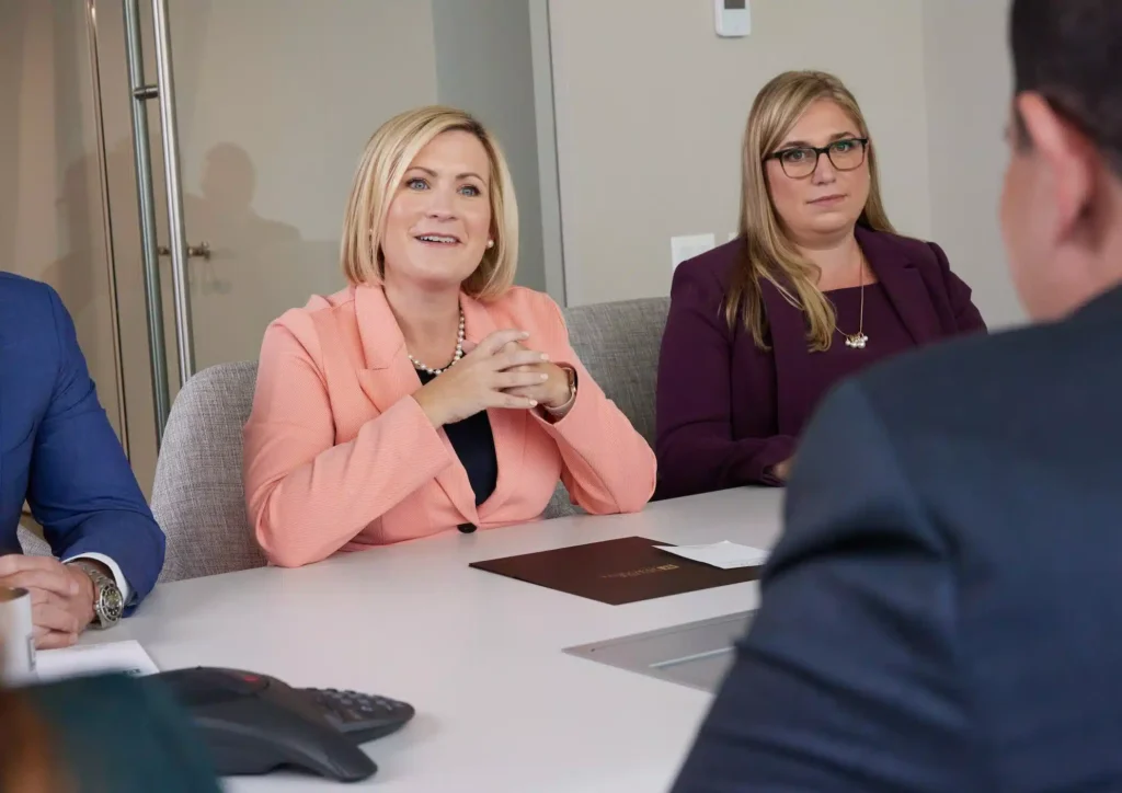 Female attorneys in professional attire consulting with client during office meeting