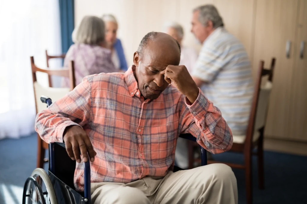 Elderly man in wheelchair looking distressed in nursing home