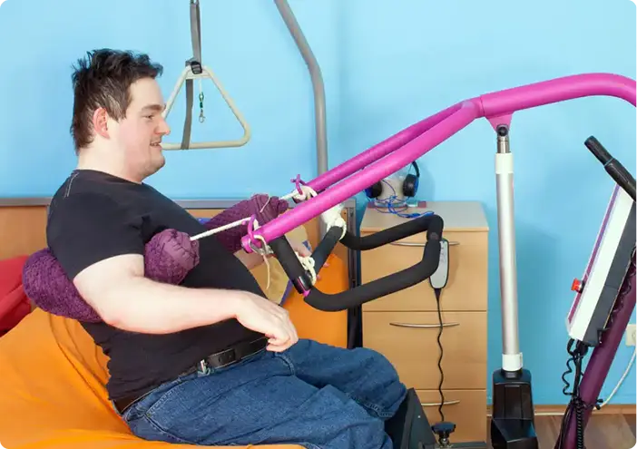 Young man using adaptive exercise equipment during physical therapy session