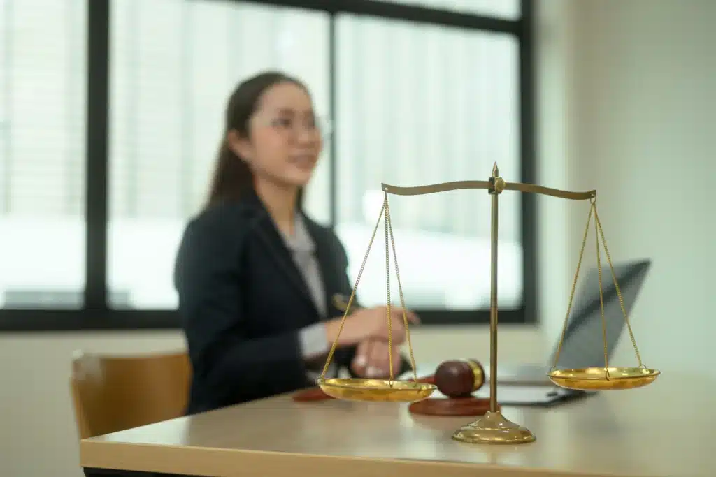 Scales of justice on desk with female attorney in background
