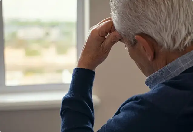 An elderly man with his hand on his head
