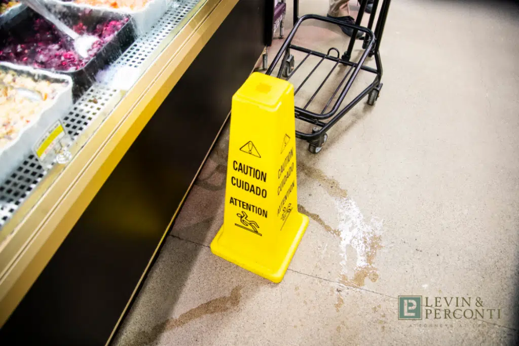 yellow "caution" cone in a store near a liquid spill and grocery cart
