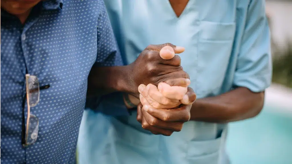 health care worker holding a patient's hand in support and care