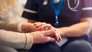 Nurse holding an elderly patient's hand